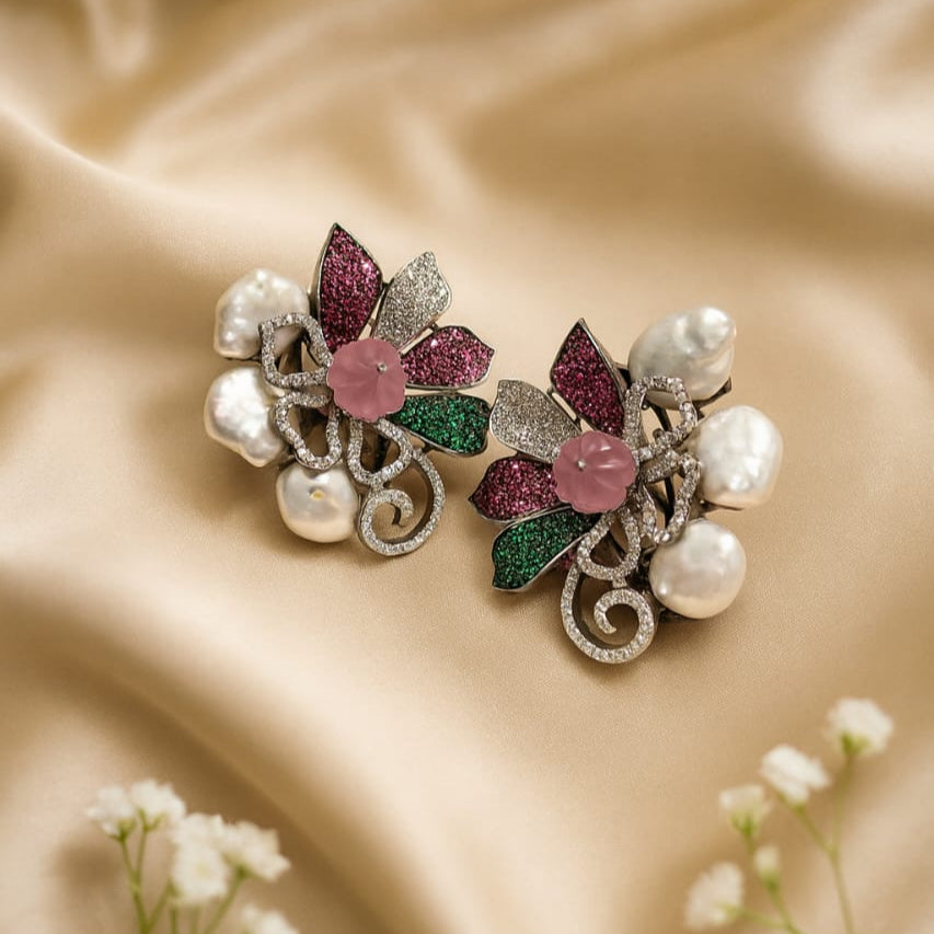 Pair of decorative earrings with floral design on a beige fabric background